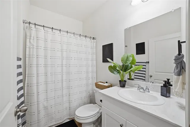 a bathroom with a sink a toilet a mirror and shower