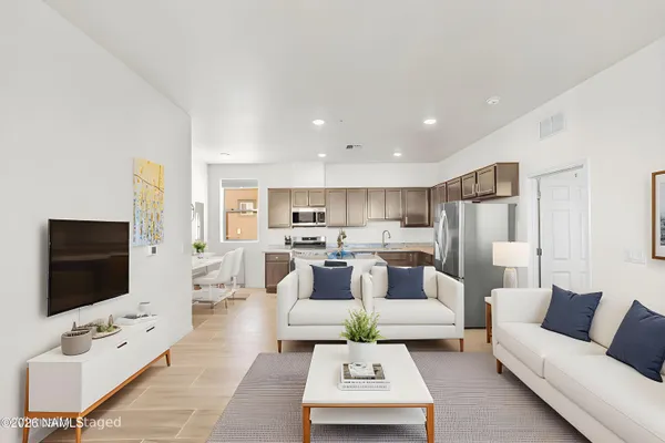 a living room with furniture a flat screen tv and kitchen view