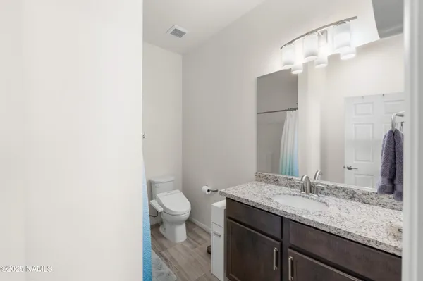 a bathroom with a granite countertop sink a toilet and a large mirror