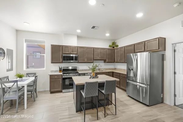 a kitchen with a sink a microwave a refrigerator and chairs