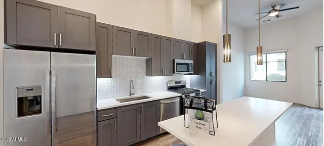 a kitchen with stainless steel appliances a refrigerator a sink a stove and white cabinets with wooden floor