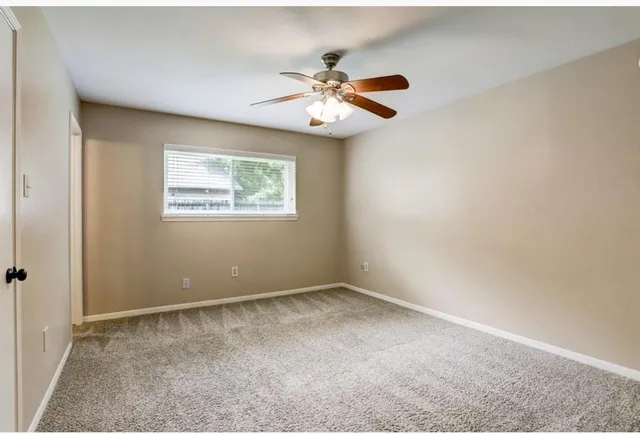 an empty room with chandelier fan and windows
