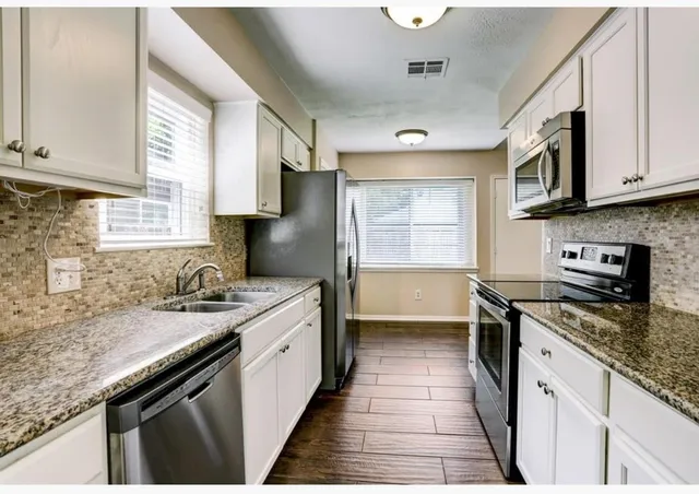 a kitchen with stainless steel appliances granite countertop a sink stove and cabinets