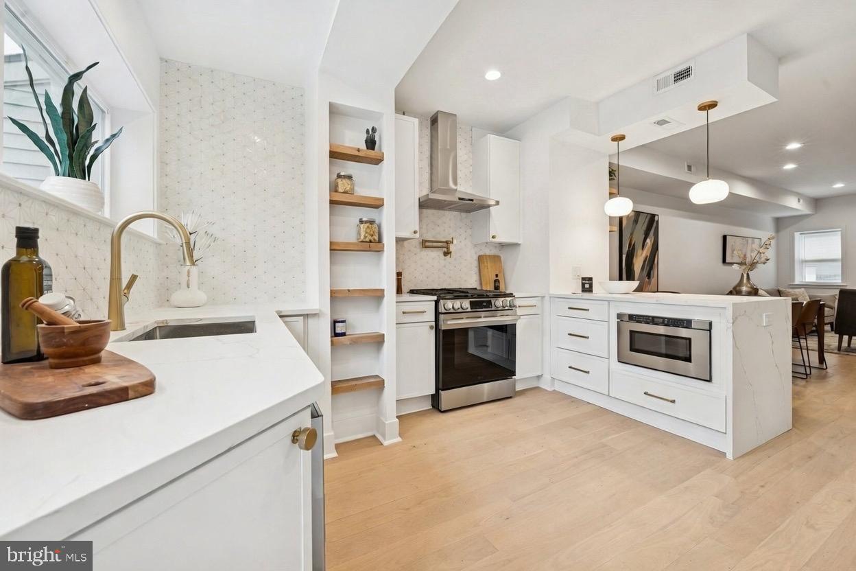 1019 Ellsworth Street Philadelphia, PA 19147 - Photo 2 of 31 a kitchen with white cabinets and stainless steel appliances