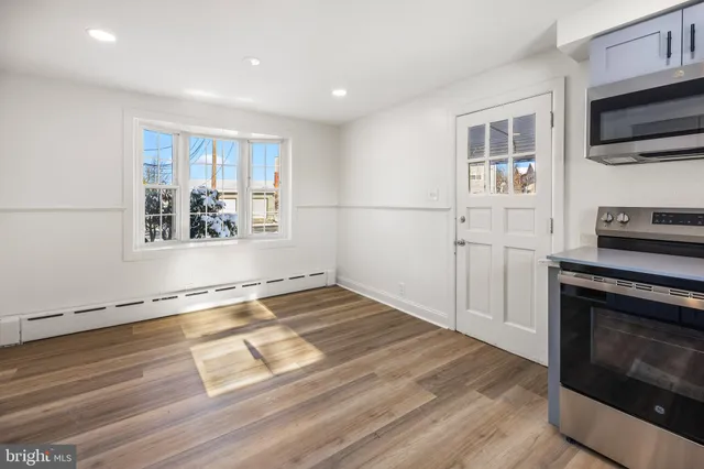 a view of a livingroom with wooden floor and a kitchen