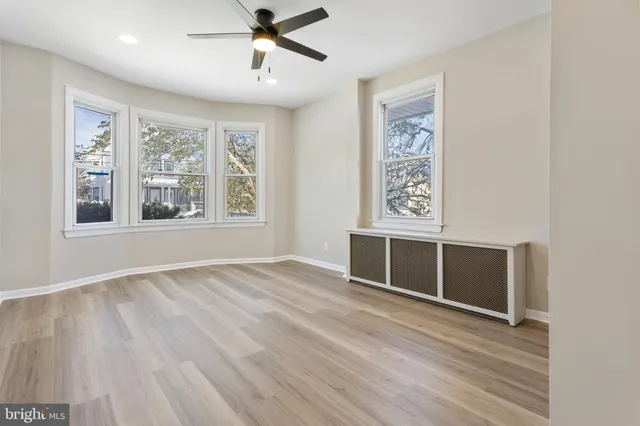a view of an empty room with a window and wooden floor