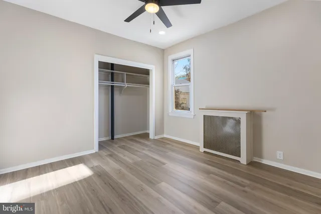 an empty room with wooden floor cabinet and windows