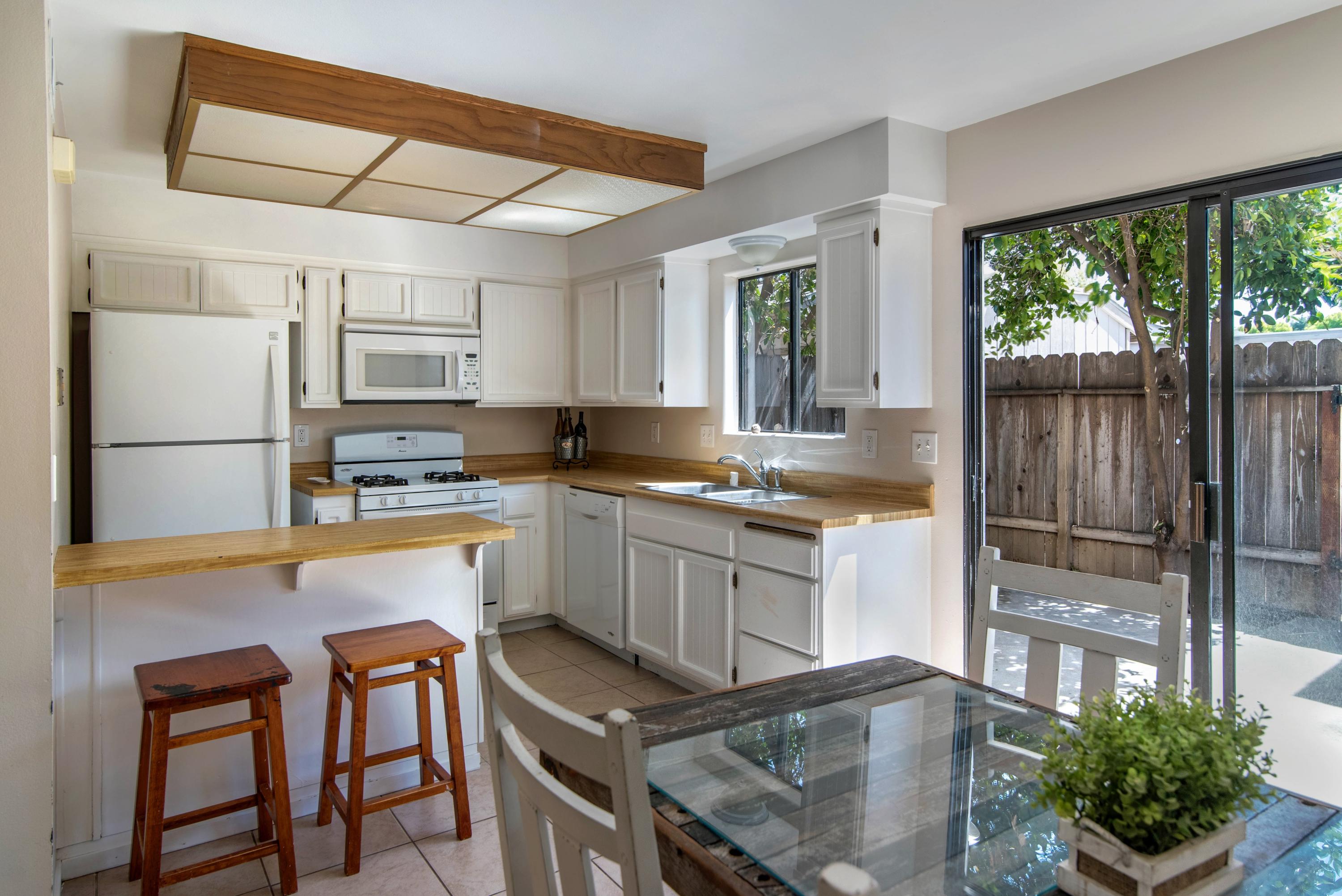 202 North R Street Lompoc, CA 93436 - Photo 5 of 12 a kitchen with kitchen island granite countertop a table chairs microwave and cabinets