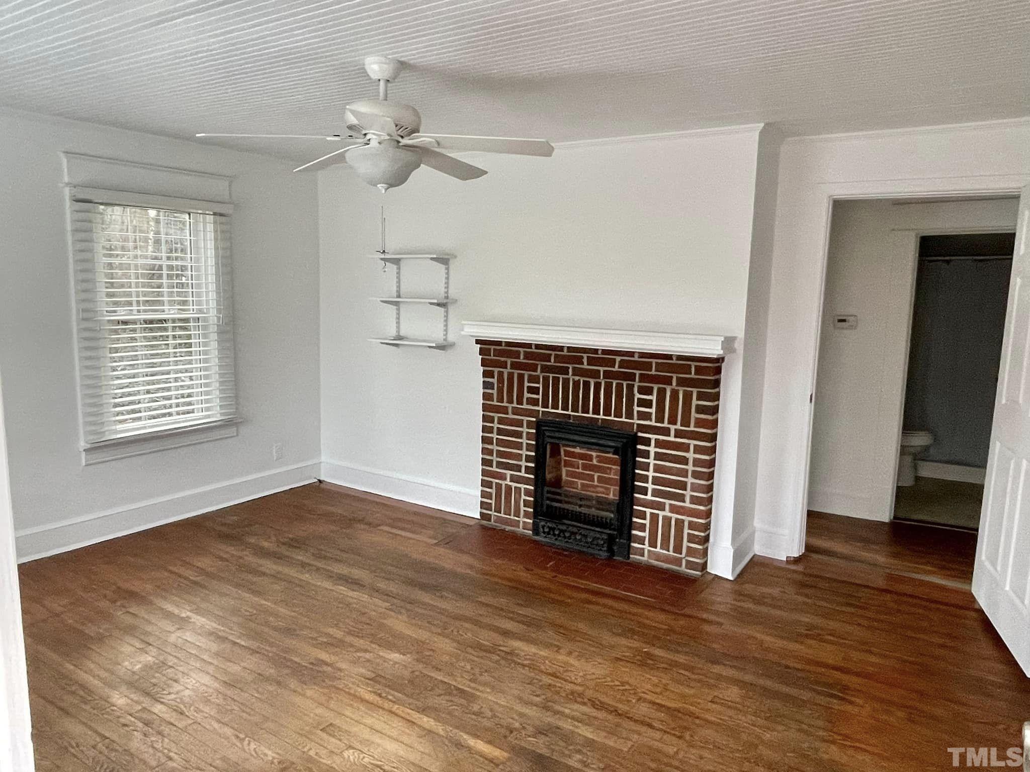 207 Broad Street Roxboro, NC 27573 - Photo 2 of 17 an empty room with wooden floor fireplace and windows