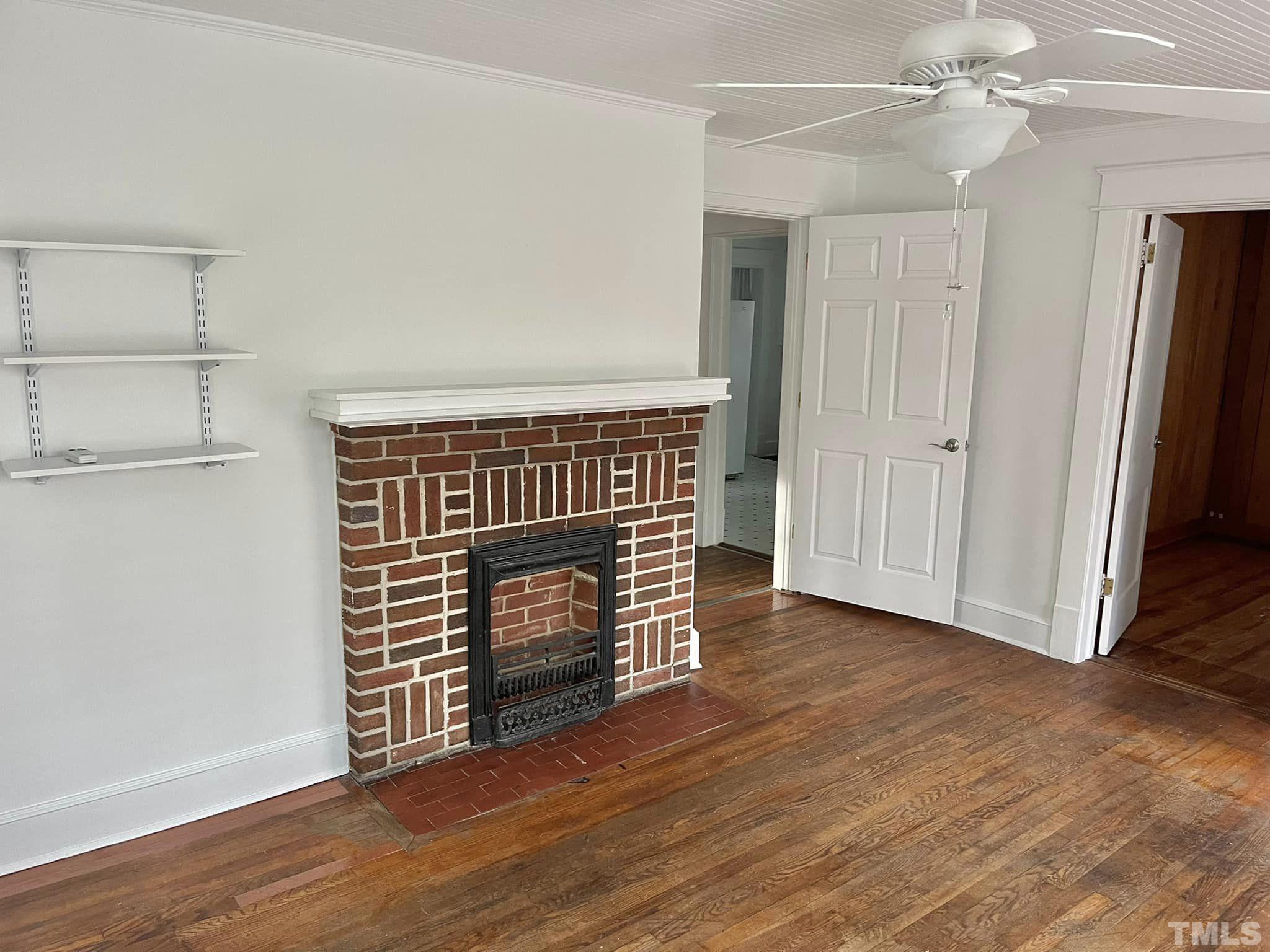 207 Broad Street Roxboro, NC 27573 - Photo 3 of 17 a view of an empty room with wooden floor and a fireplace