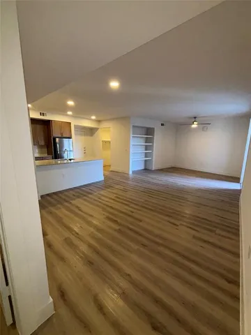 a view of an empty room with kitchen and a window