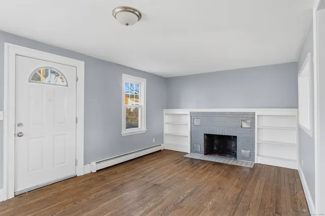 an empty room with wooden floor fireplace and windows