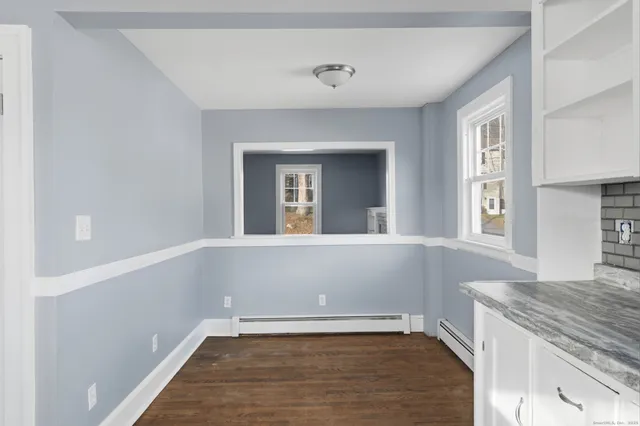 a view of an empty room with window and wooden floor