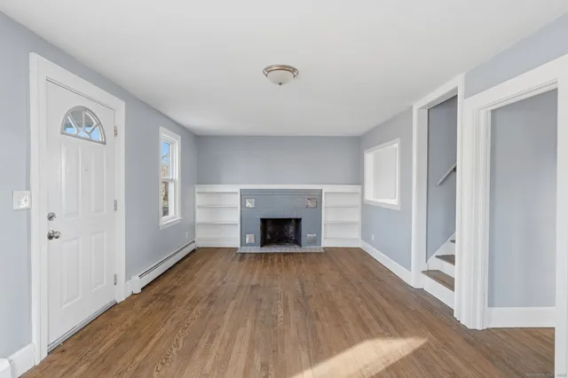 a view of a livingroom with wooden floor a fireplace and window