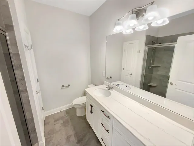 a spacious bathroom with a double vanity sink a toilet and a mirror