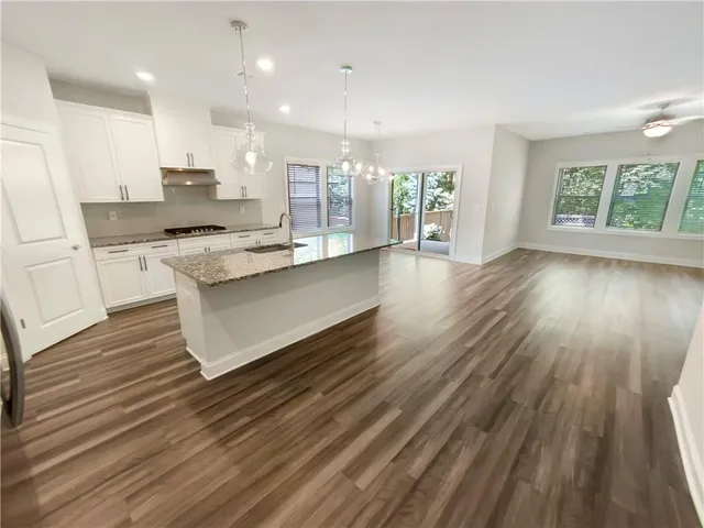 a large kitchen with cabinets wooden floor and stainless steel appliances
