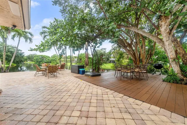 a view of a patio with table and chairs potted plants and large tree