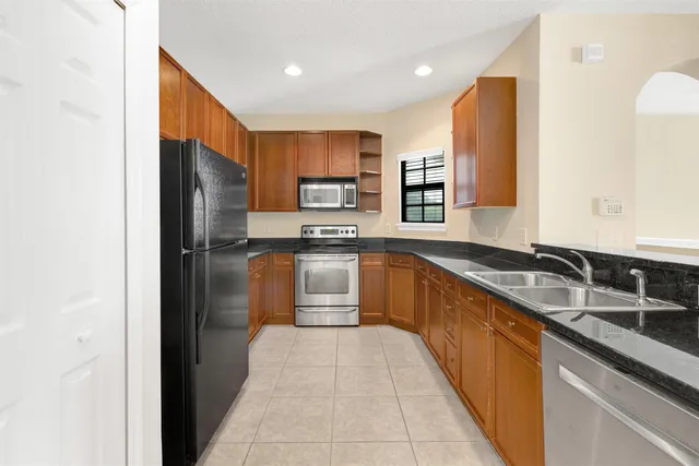 a large kitchen with stainless steel appliances kitchen island granite countertop a sink refrigerator and cabinets