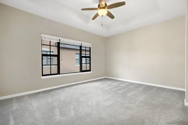 an empty room with windows and chandelier fan