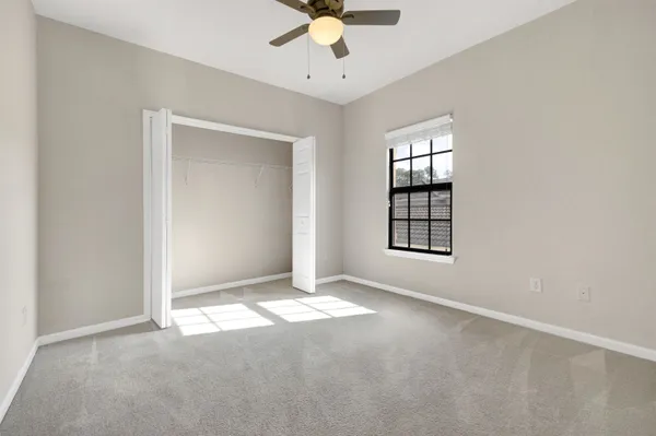 an empty room with windows and ceiling fan