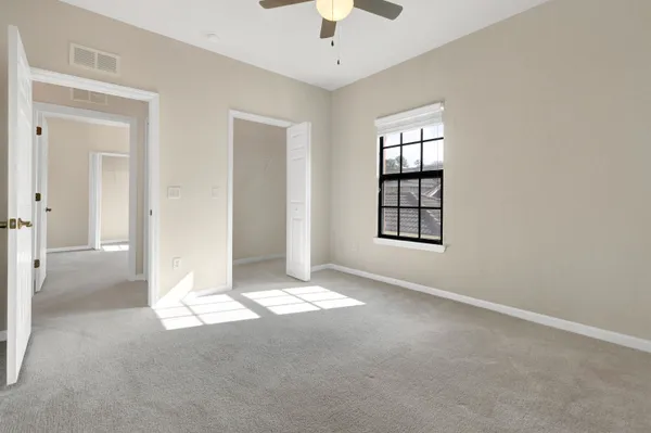 an empty room with windows and chandelier fan