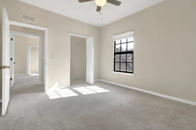 an empty room with windows and chandelier fan
