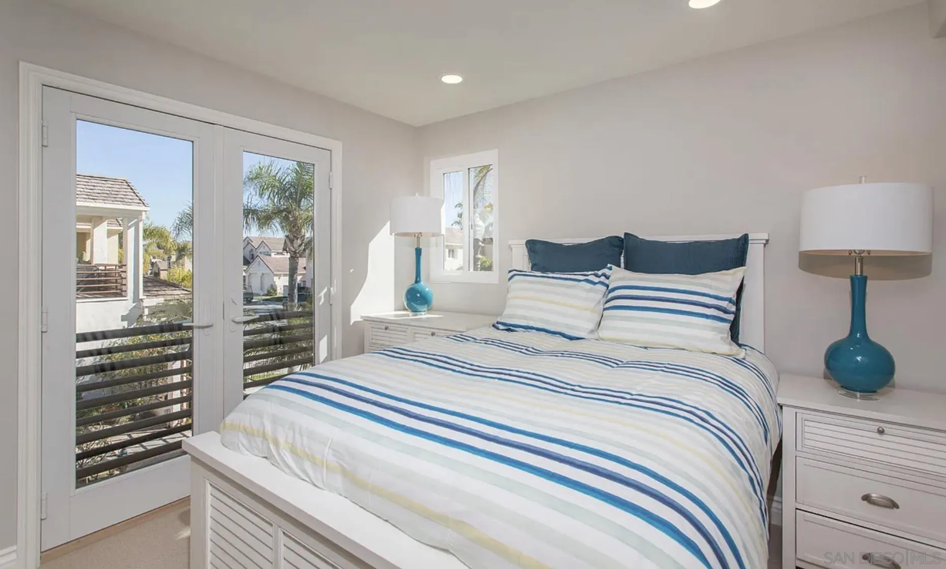 48 Spinnaker Way Coronado, CA 92118 - Photo 26 of 29 a bedroom with a balcony a bed and a lamp on dresser