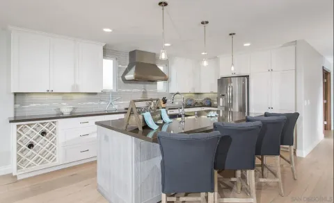 a kitchen with stainless steel appliances granite countertop a sink a stove a refrigerator and white cabinets