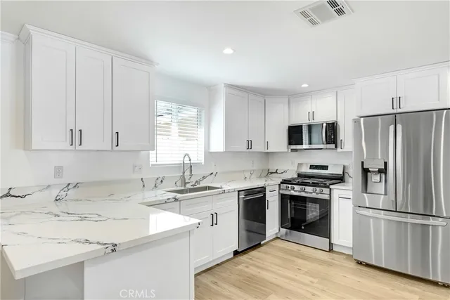 a kitchen with a sink stove a refrigerator and white cabinets