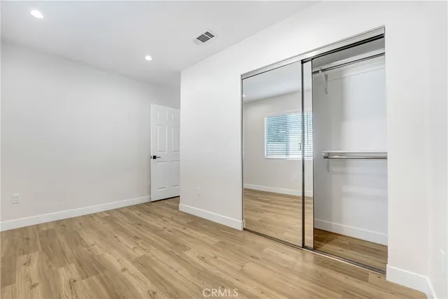 an empty room with wooden floor closet and windows