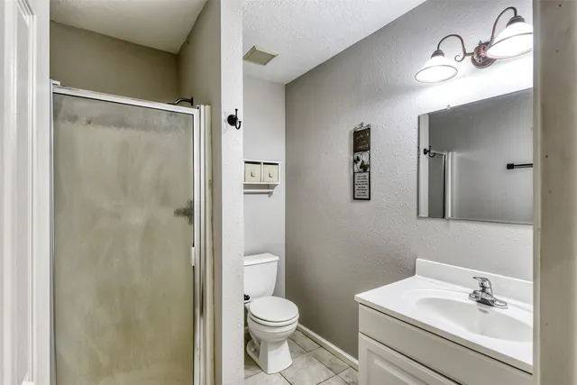 a bathroom with a shower sink vanity mirror and toilet