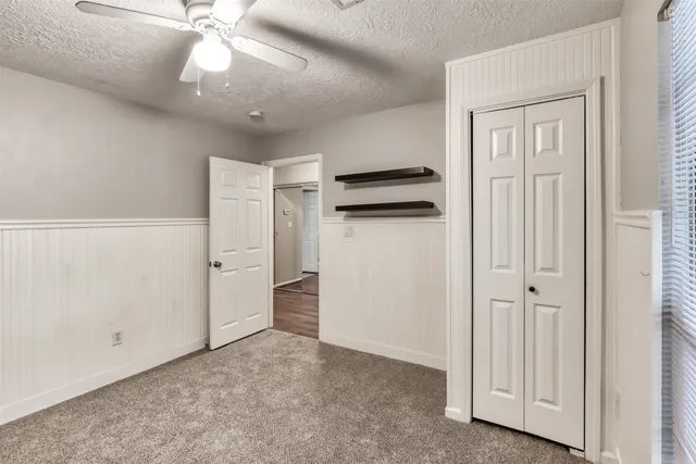 an empty room with closet and a ceiling fan
