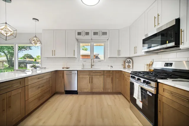 a kitchen with stainless steel appliances granite countertop a stove a sink and a microwave