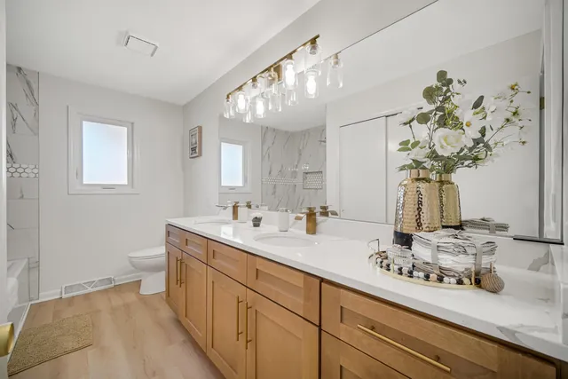 a bathroom with a granite countertop double vanity and a mirror