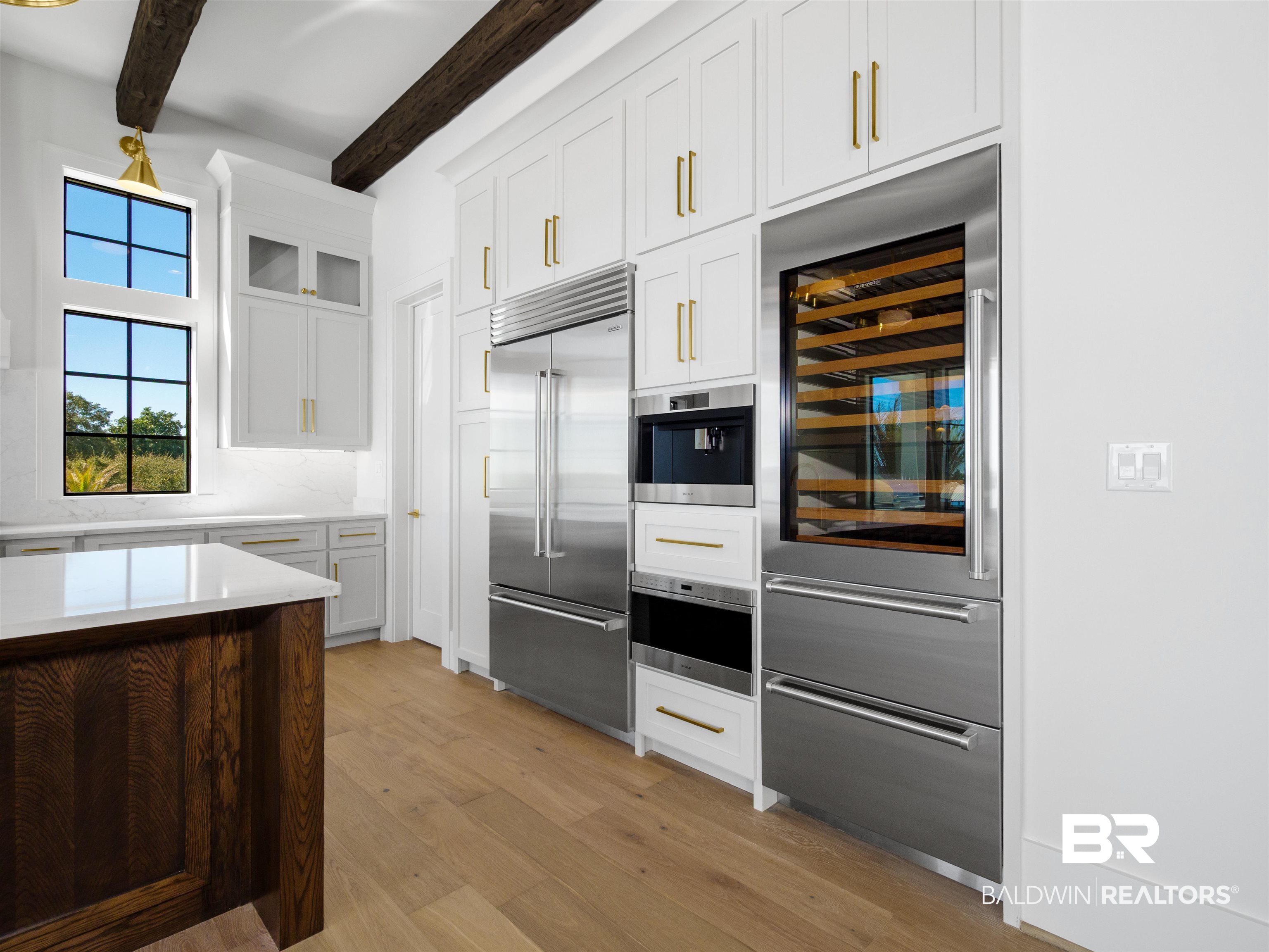 31292 River Road Orange Beach, AL 36561 - Photo 7 of 48 Kitchen featuring wine cooler, stainless steel appliances, white cabinetry, light countertops, and beam ceiling