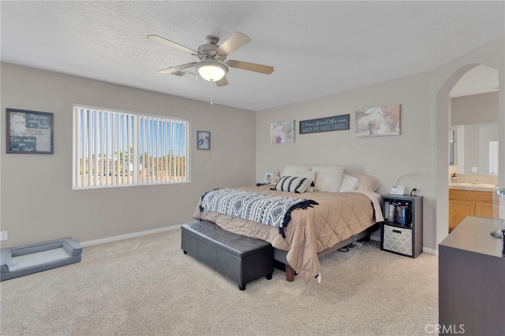 12871 Alta Vista Road Pinon Hills, CA 92372 - Photo 23 of 40 a spacious bedroom with a bed and a chandelier