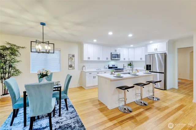 a kitchen with kitchen island stainless steel appliances a dining table chairs and granite counter tops