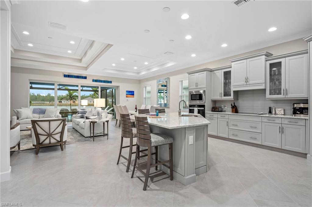 8795 Calypso Court Naples, FL 34113 - Photo 9 of 49 a kitchen with stainless steel appliances kitchen island granite countertop a sink and cabinets