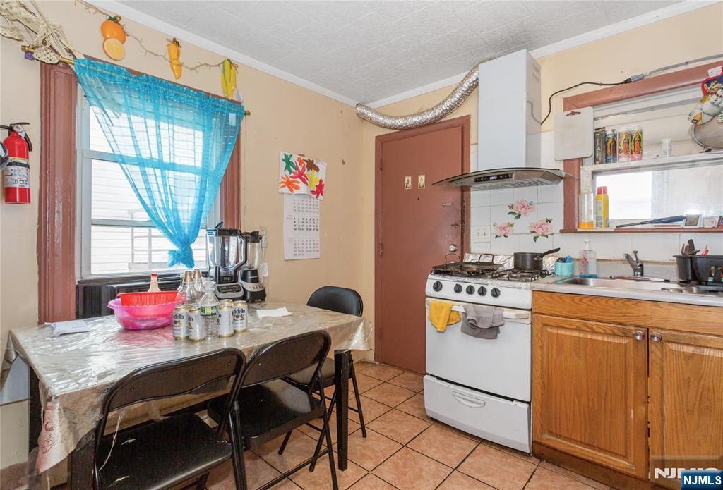 120-122 Lodi Street Hackensack, NJ 07601 - Photo 25 of 50 a dining room with a stove a sink cabinetry and a dining table