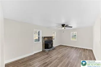 an empty room with wooden floor a ceiling fan and windows