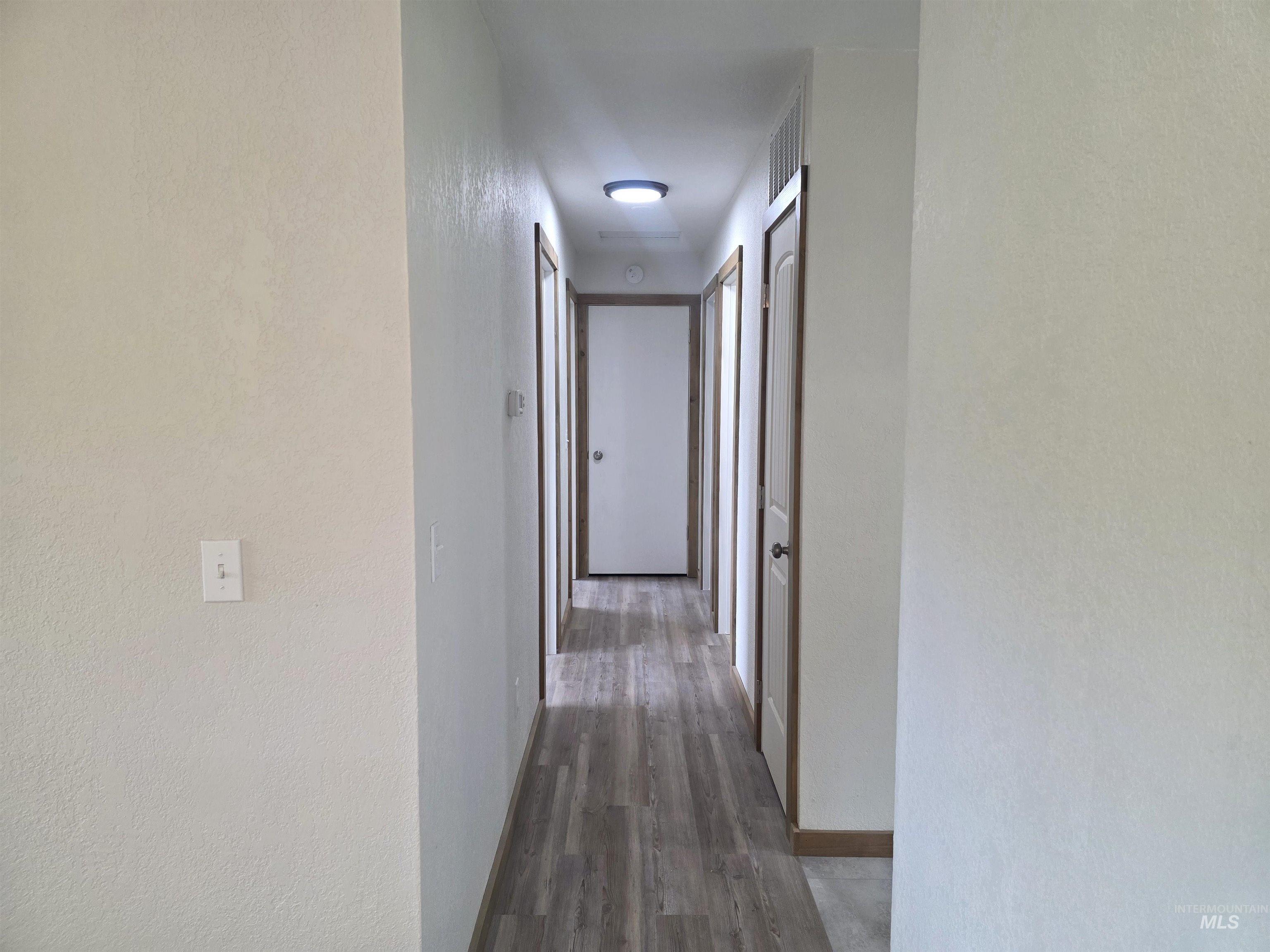 310 Fir Road Kamiah, ID 83536 - Photo 18 of 32 Hallway featuring wood-finish flooring, light-colored walls, and multiple doors with wood trim