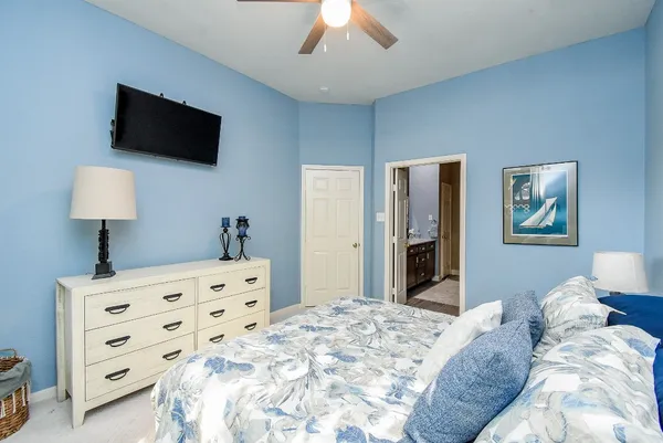 a bedroom with a bed a flat tv screen and a dresser