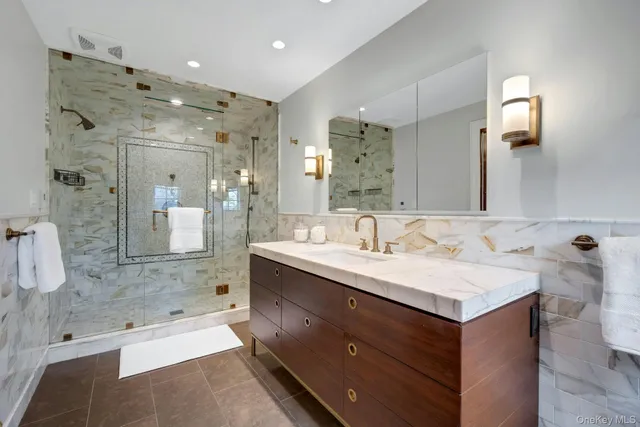 a bathroom with a sink double vanity granite tub shower and a mirror