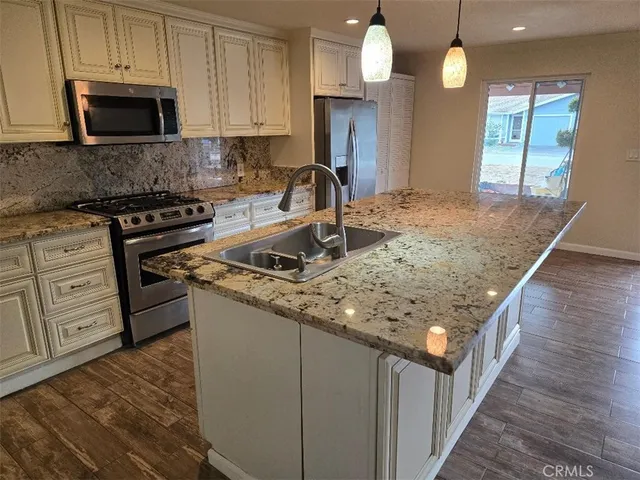 a kitchen with stainless steel appliances granite countertop a stove a sink and a microwave