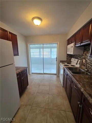 a kitchen with a sink a stove top oven and a refrigerator