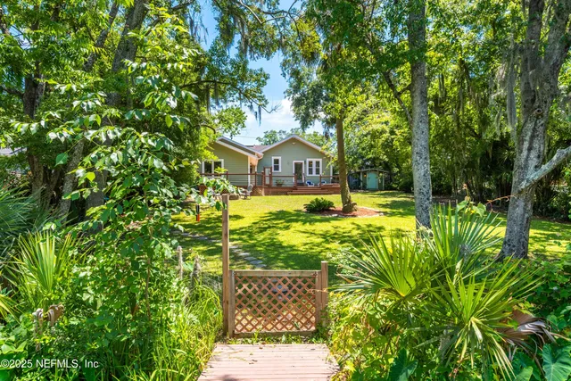 a view of a house with a big yard and large trees