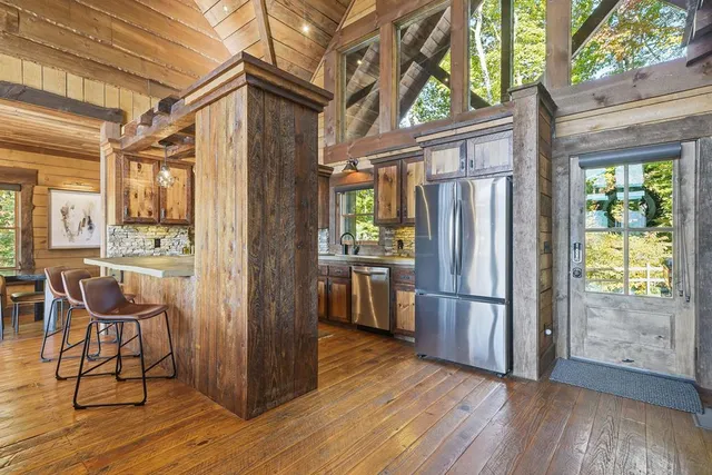 a kitchen with stainless steel appliances granite countertop a refrigerator a stove a sink and wooden floors