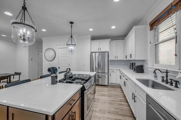 a kitchen with stainless steel appliances a sink a stove a refrigerator and cabinets