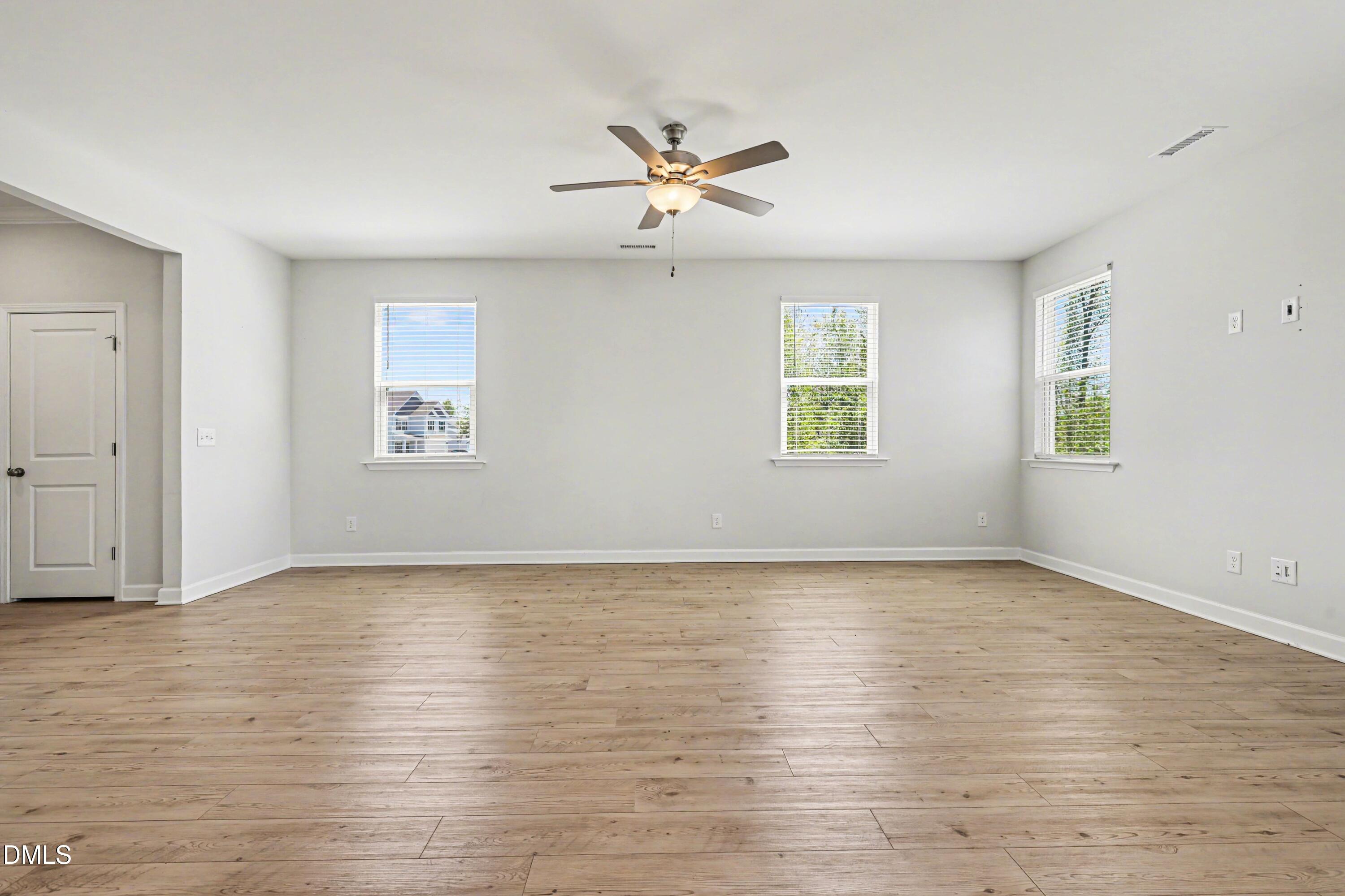 90 Rigsby Avenue Four Oaks, NC 27524 - Photo 16 of 43 an empty room with wooden floor chandelier fan and windows
