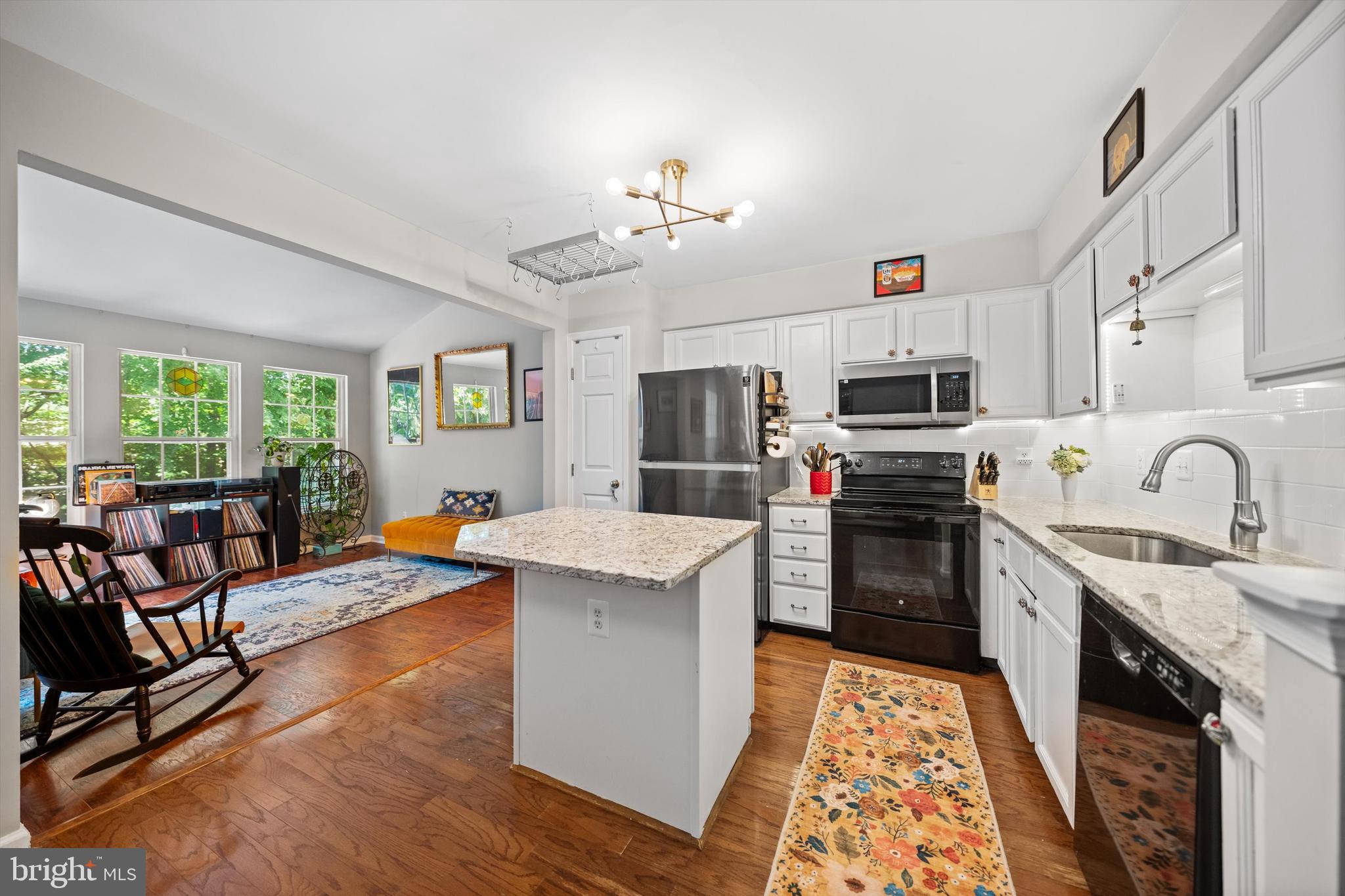 12794 Silvia Loop Woodbridge, VA 22192 - Photo 6 of 24 a open kitchen with stainless steel appliances granite countertop a stove top oven a sink dishwasher a dining table and chairs with wooden floor